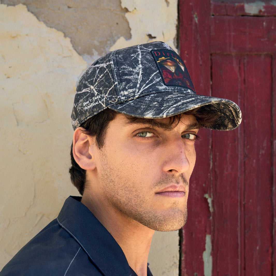 The Dirty Martini baseball cap in winter branch camo, bare branches over grey and near-black, with the red martini patch on the front.