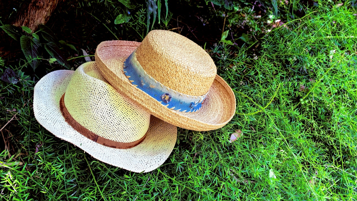 two straw hats sitting on the ground in the grass