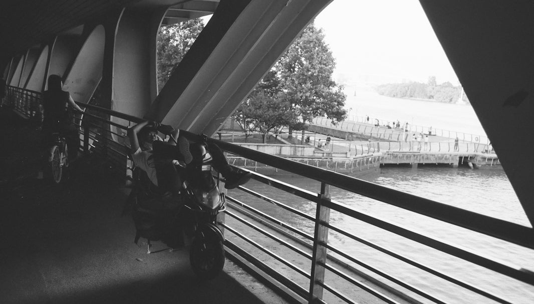 a man riding a bike down a bridge next to a body of water