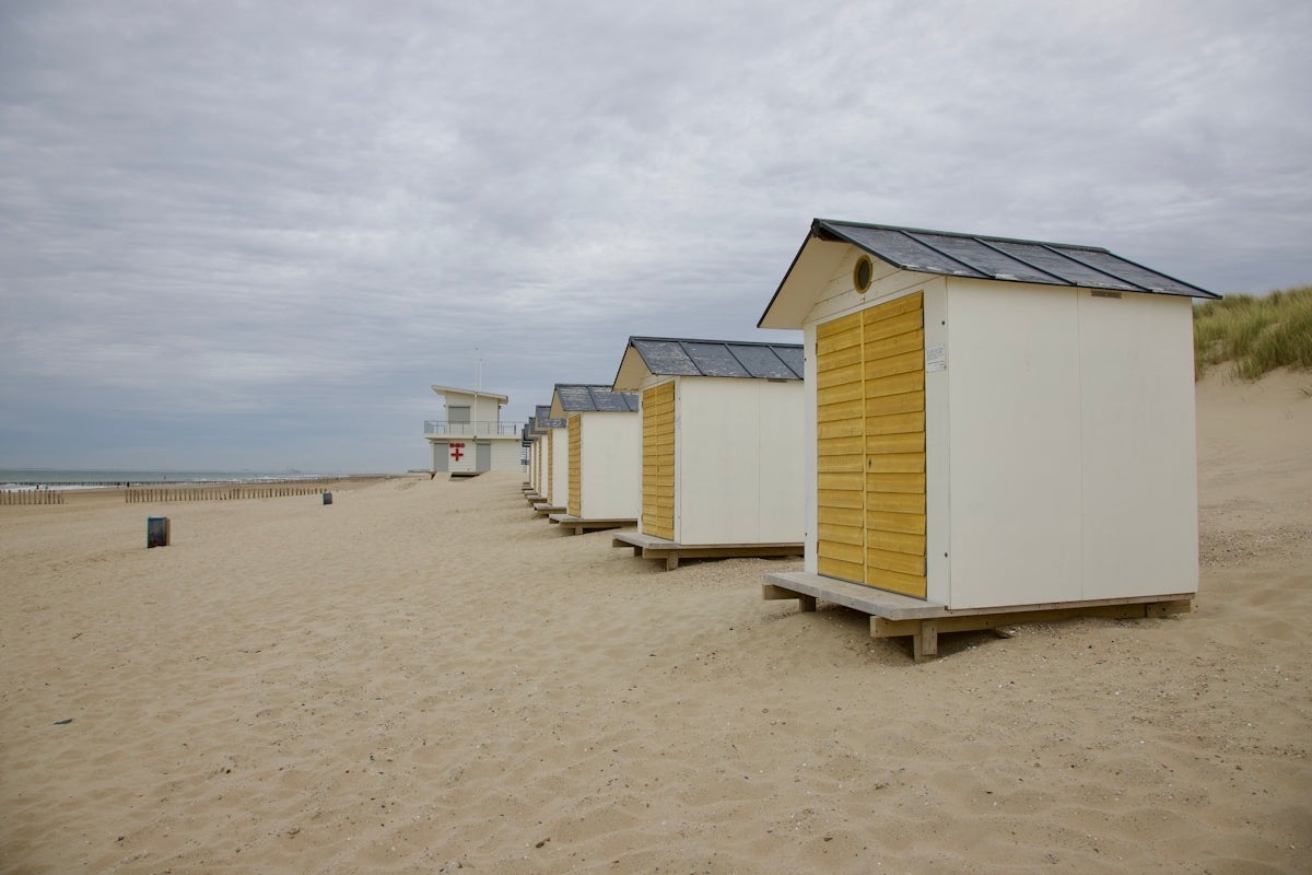 a row of beach huts sitting on top of a sandy beach