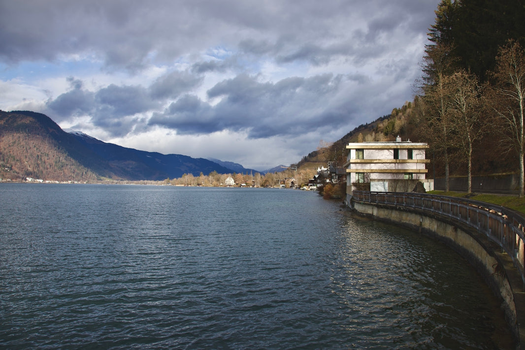 a body of water surrounded by mountains under a cloudy sky