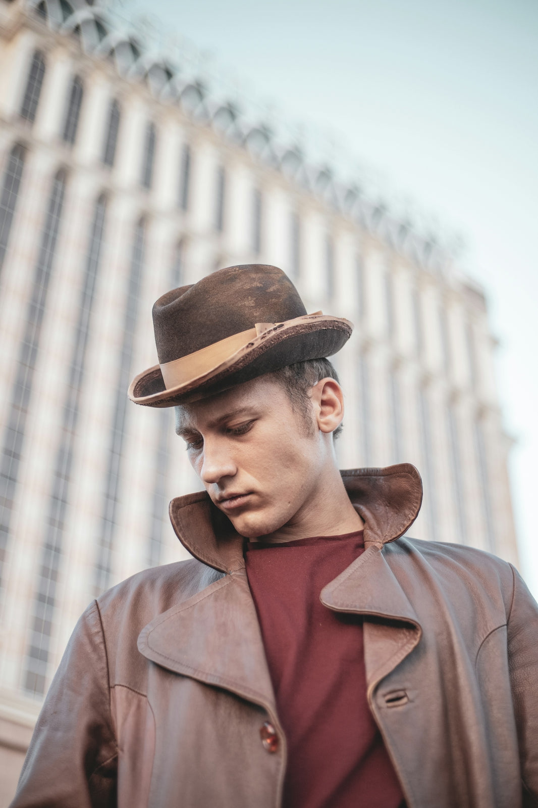 a man wearing a brown leather jacket and hat