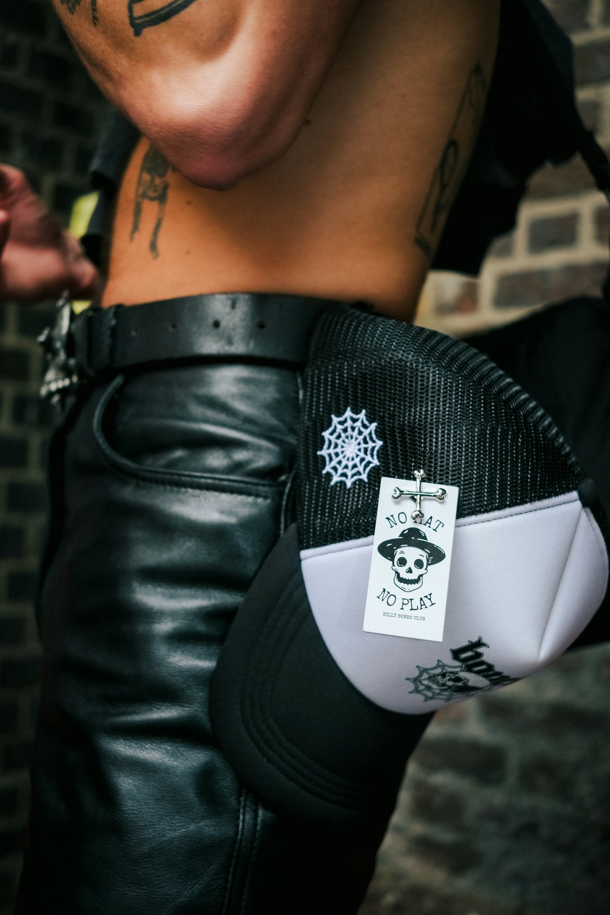 a man with a tattoo on his arm holding a pair of black leather pants