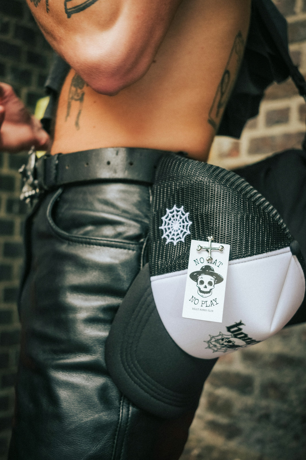 a man with tattoos holding a pair of black leather pants