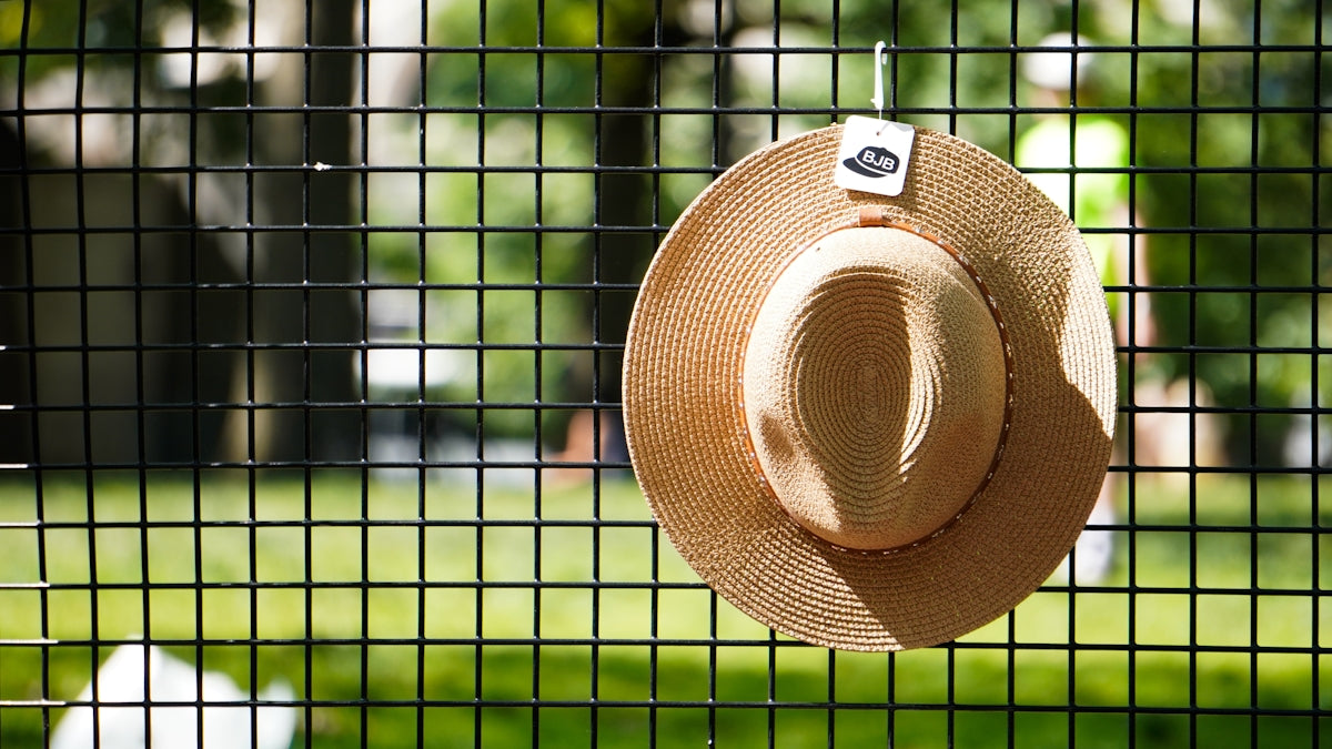 a hat hanging on a fence in a park