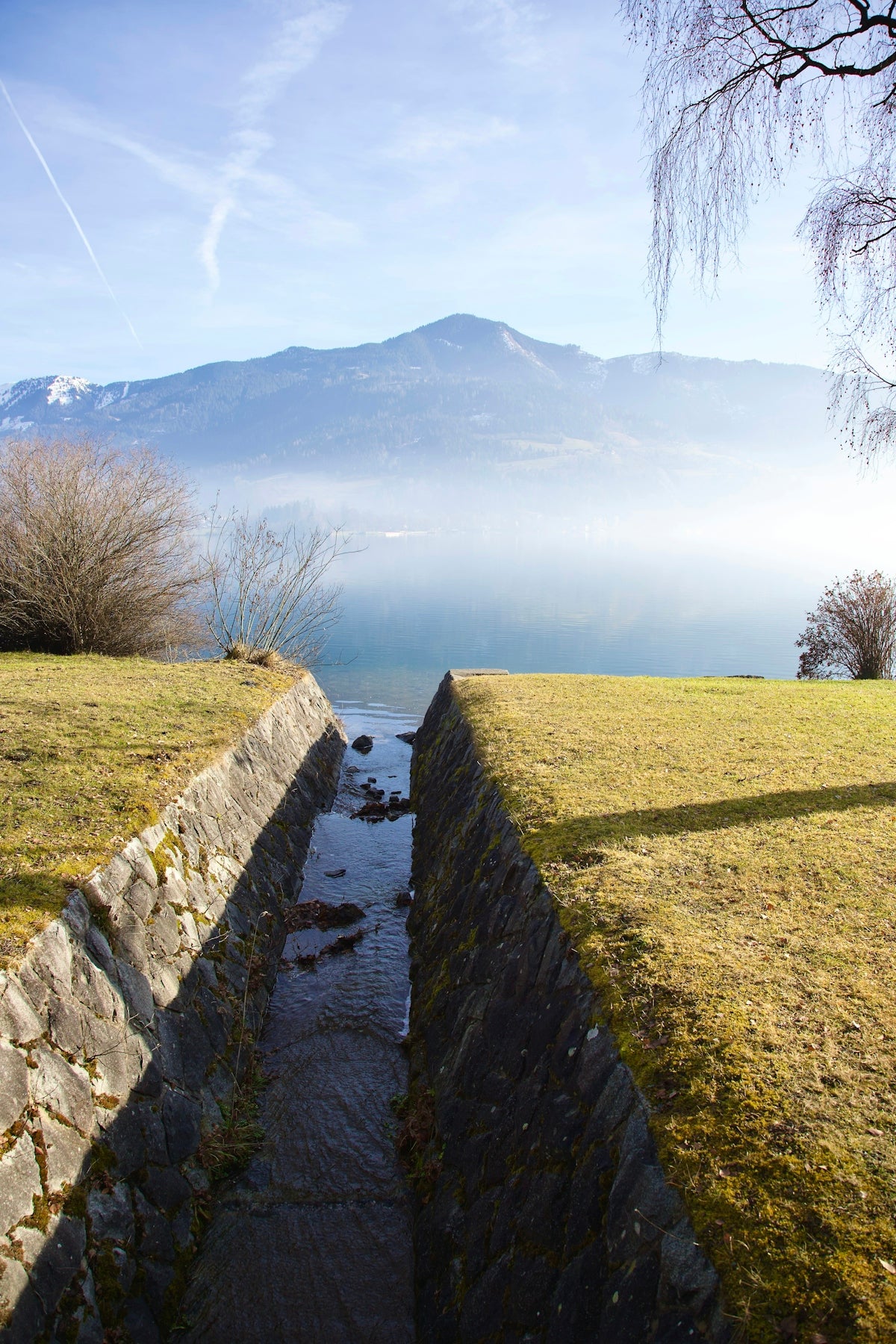 a small stream running through a grass covered field