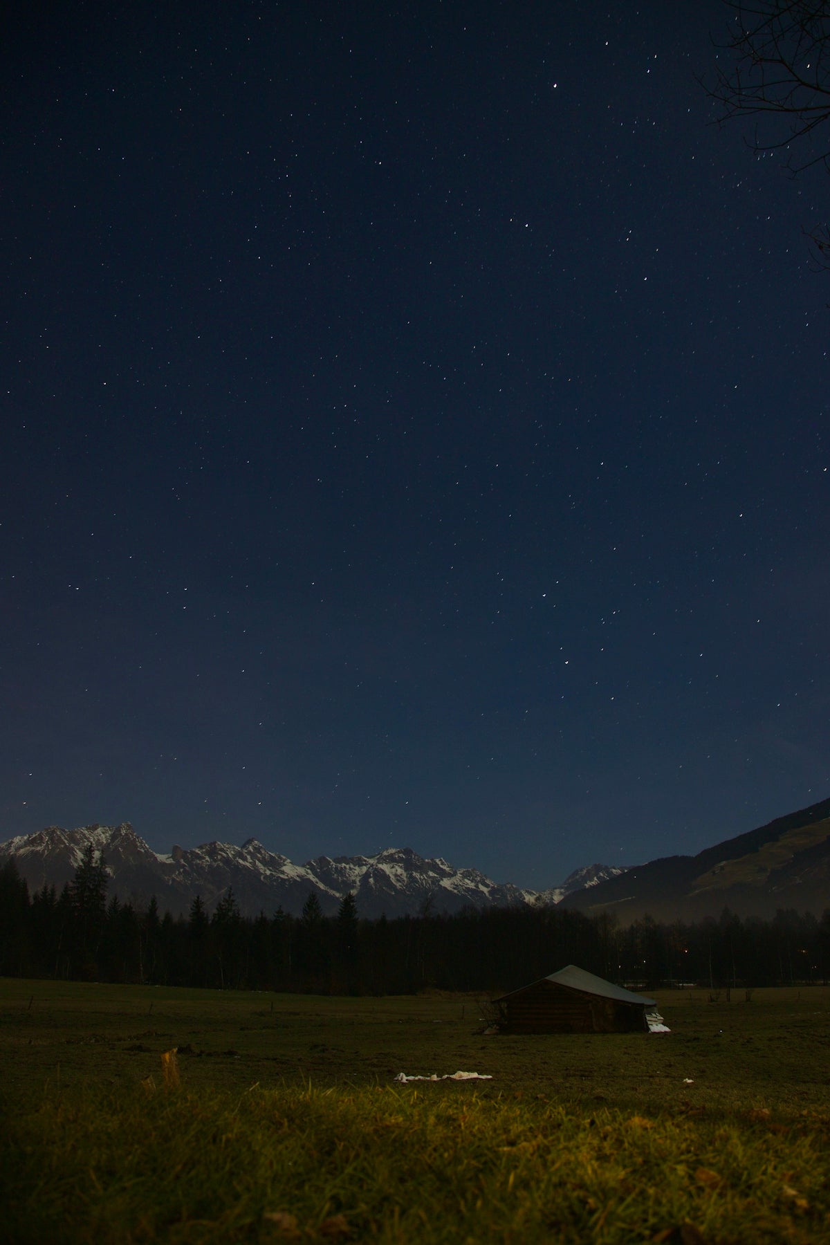 a field with a barn and mountains in the background