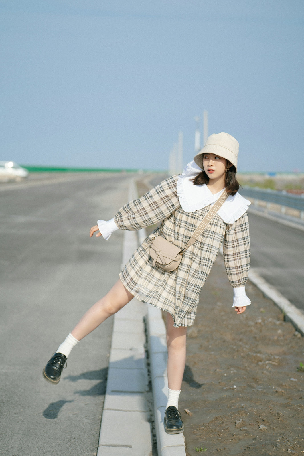 a woman in a dress and hat posing on the side of a road