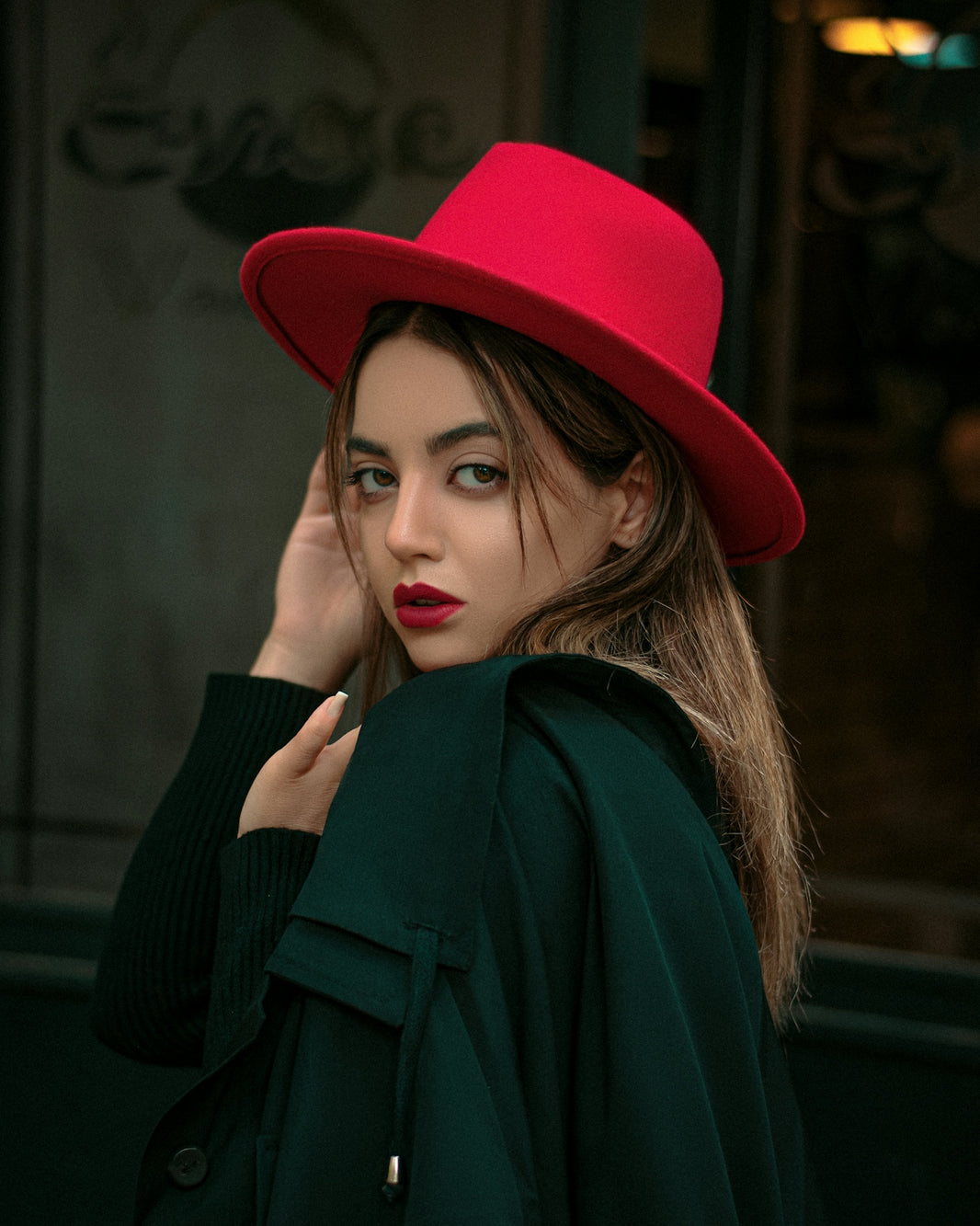 a woman wearing a red hat and green coat