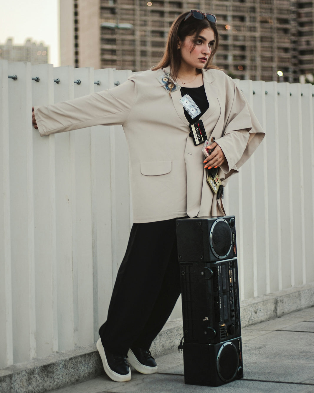 a woman leaning against a white fence holding a suitcase