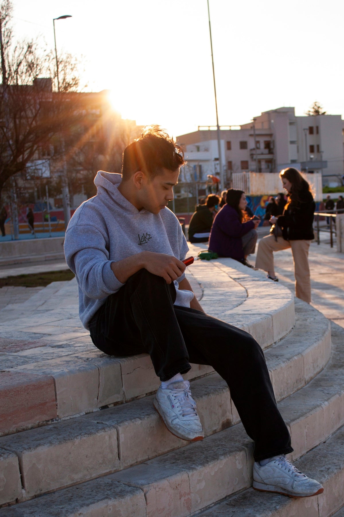 a man sitting on a stone step looking at his cell phone