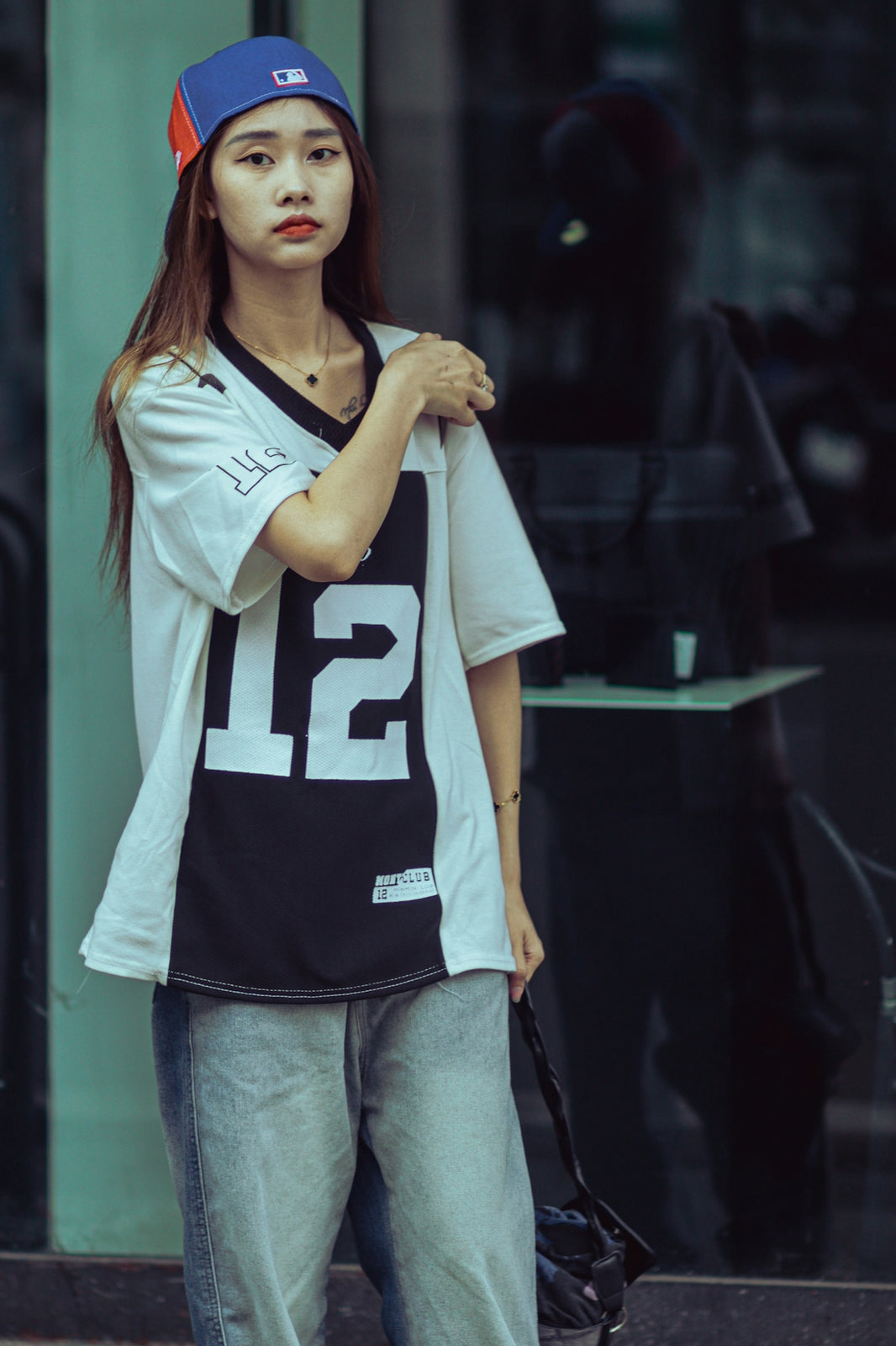 a woman standing on the street with a baseball cap on