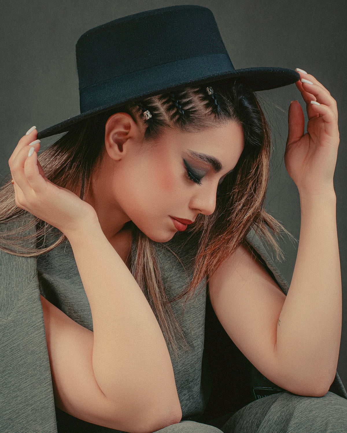 a woman wearing a black hat with her hands on her head