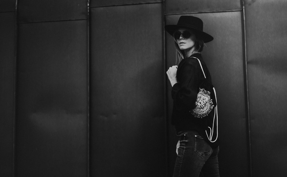 A woman standing next to a wall wearing a hat