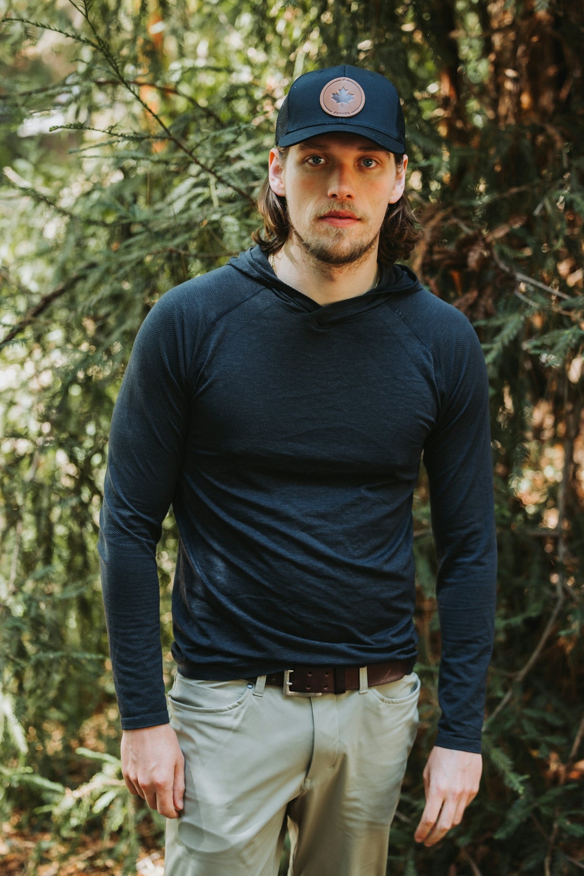 A man standing in a forest wearing a hat
