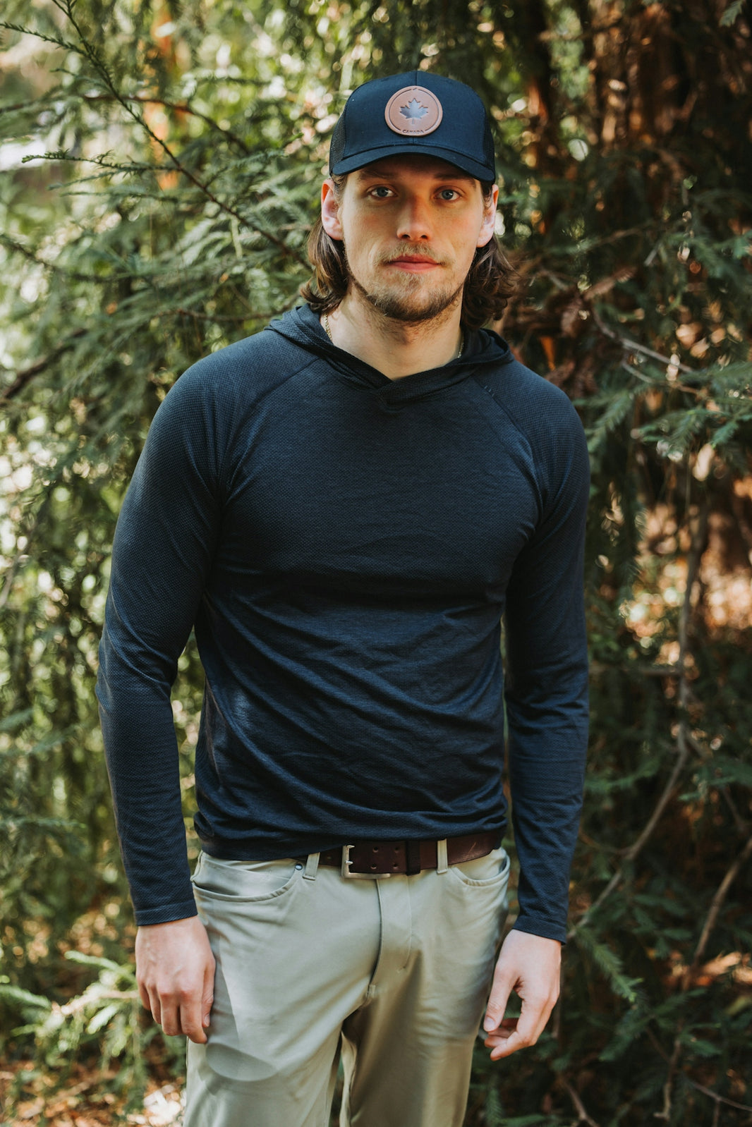 A man standing in the woods wearing a hat