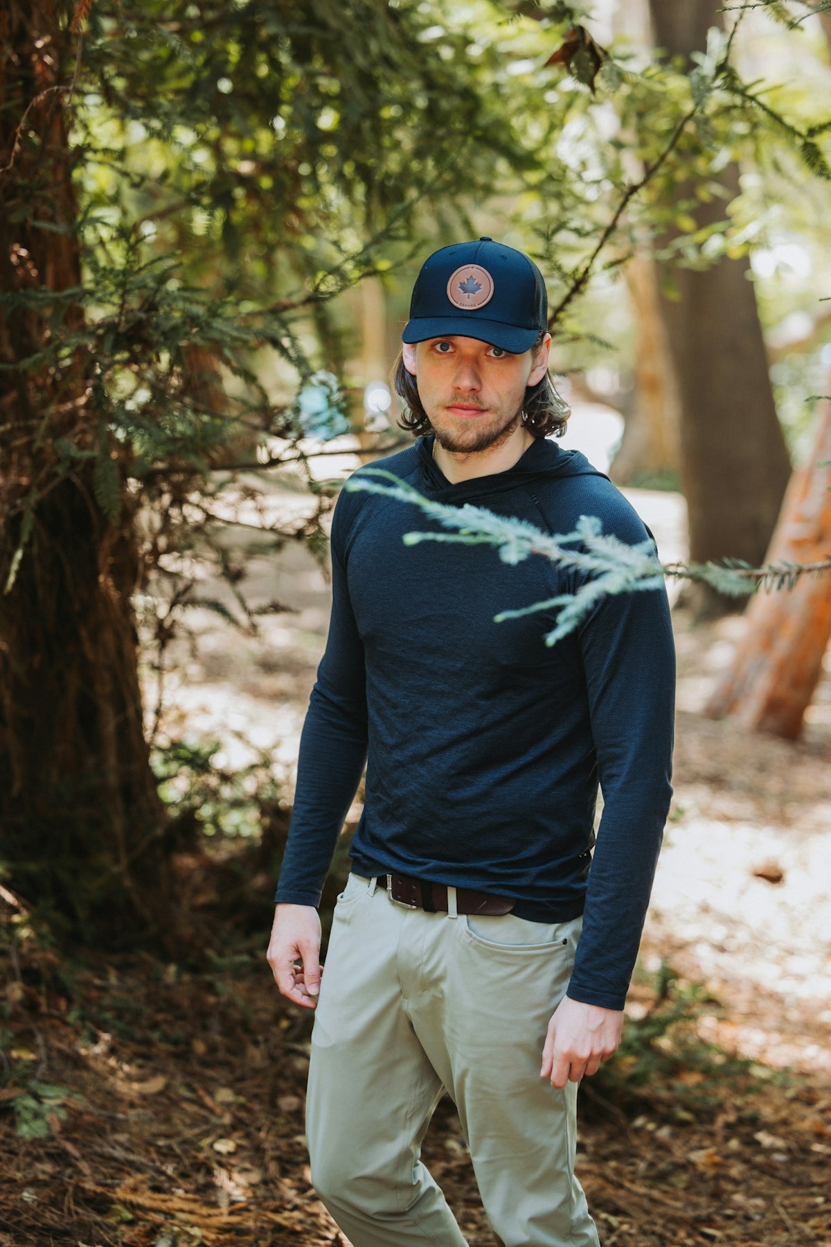 A man standing in the woods wearing a hat