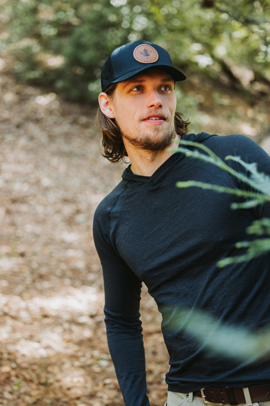 A man standing in the woods wearing a hat