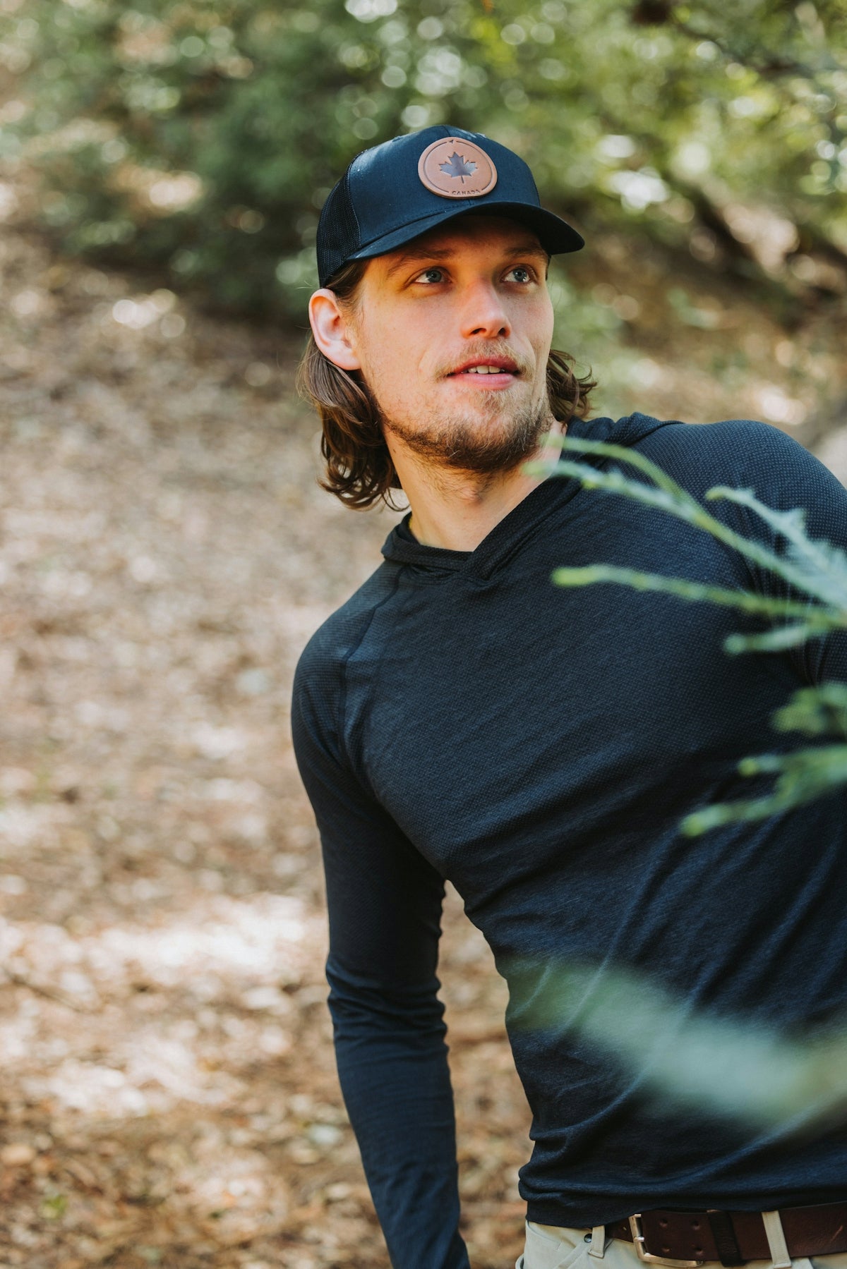 A man standing in the woods wearing a hat