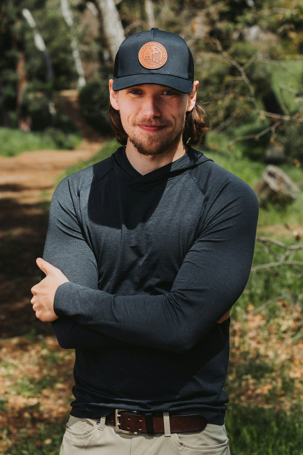 A man wearing a hat standing in the woods