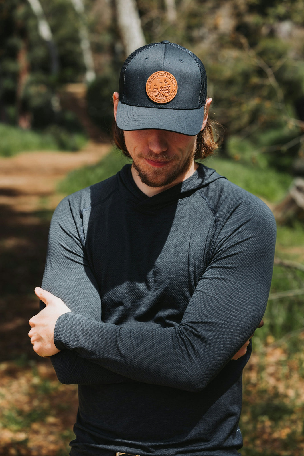 A man wearing a hat standing in the woods