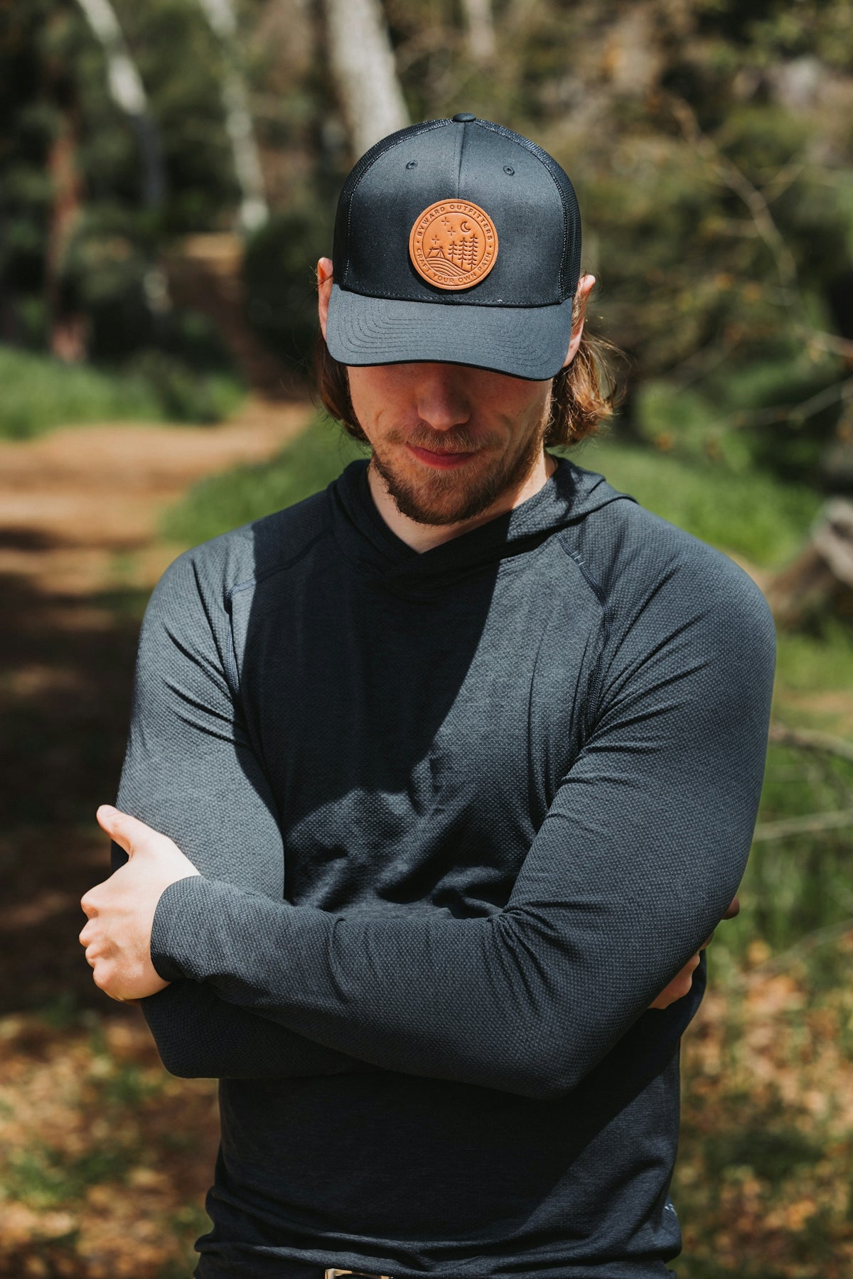 A man wearing a hat standing in the woods