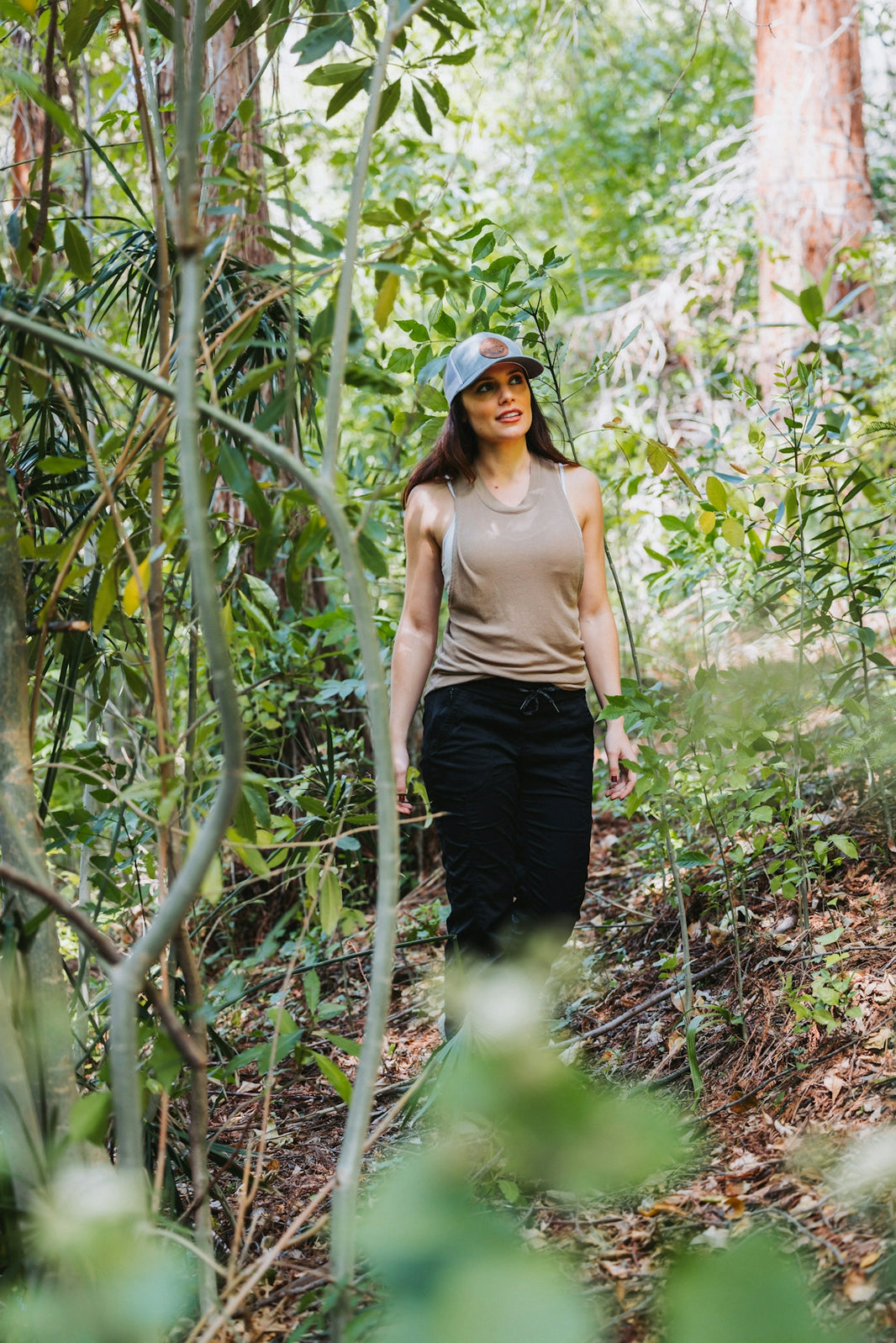 A woman in a hat is walking through the woods