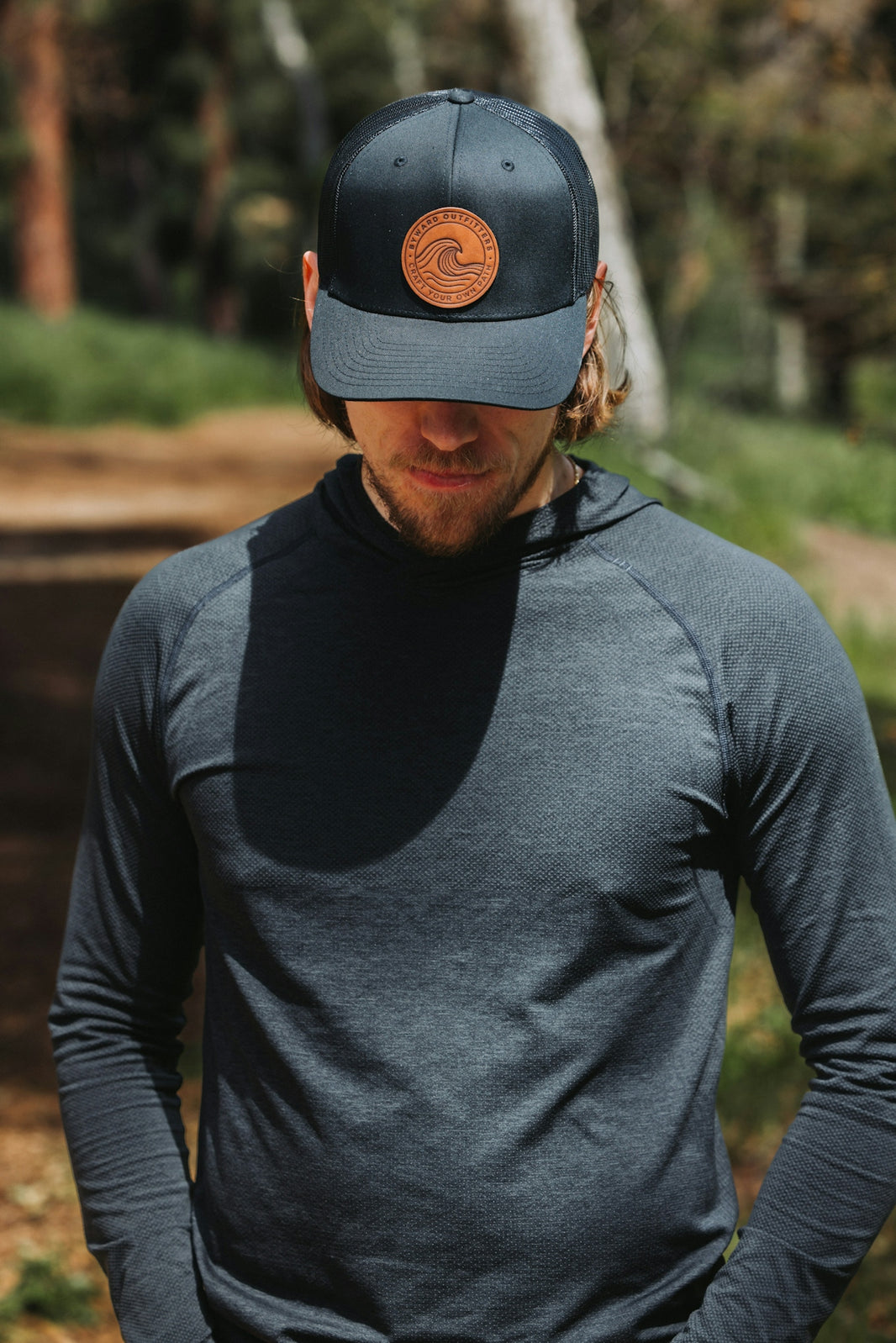A man wearing a hat standing in the woods