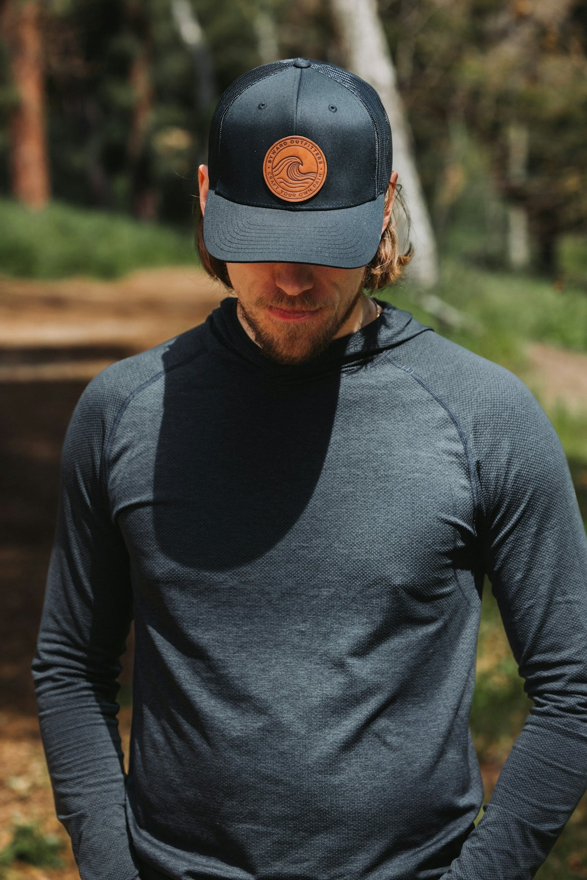 A man wearing a hat standing in the woods
