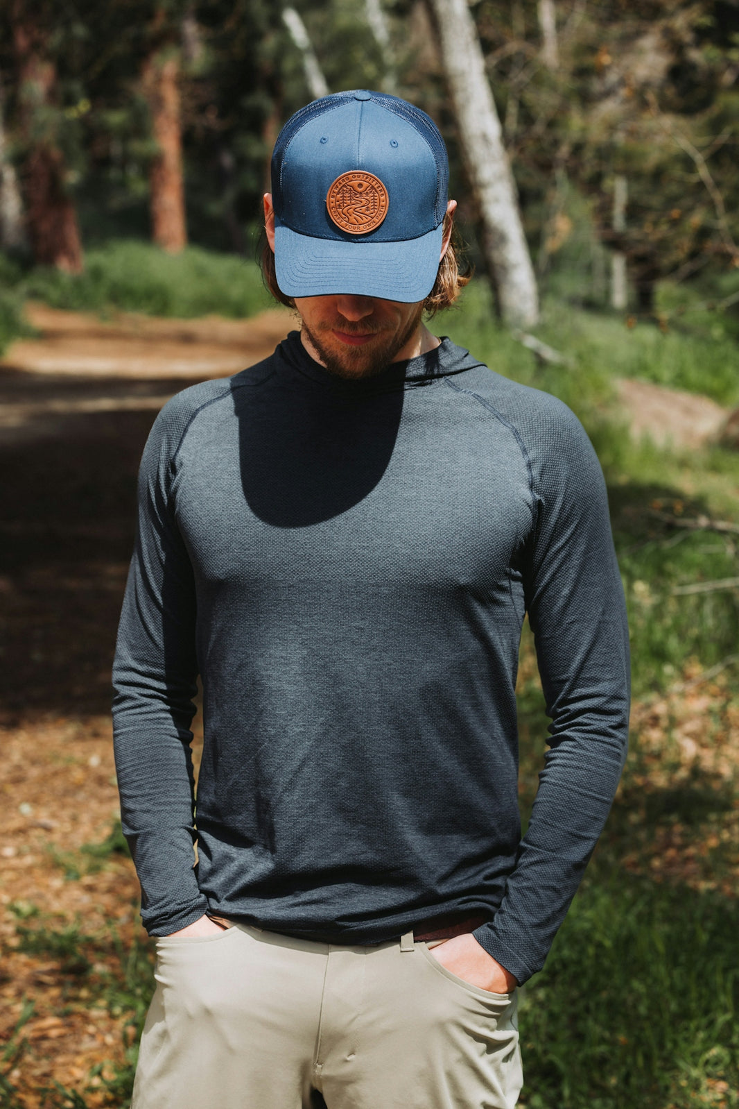 A man standing in the woods wearing a hat