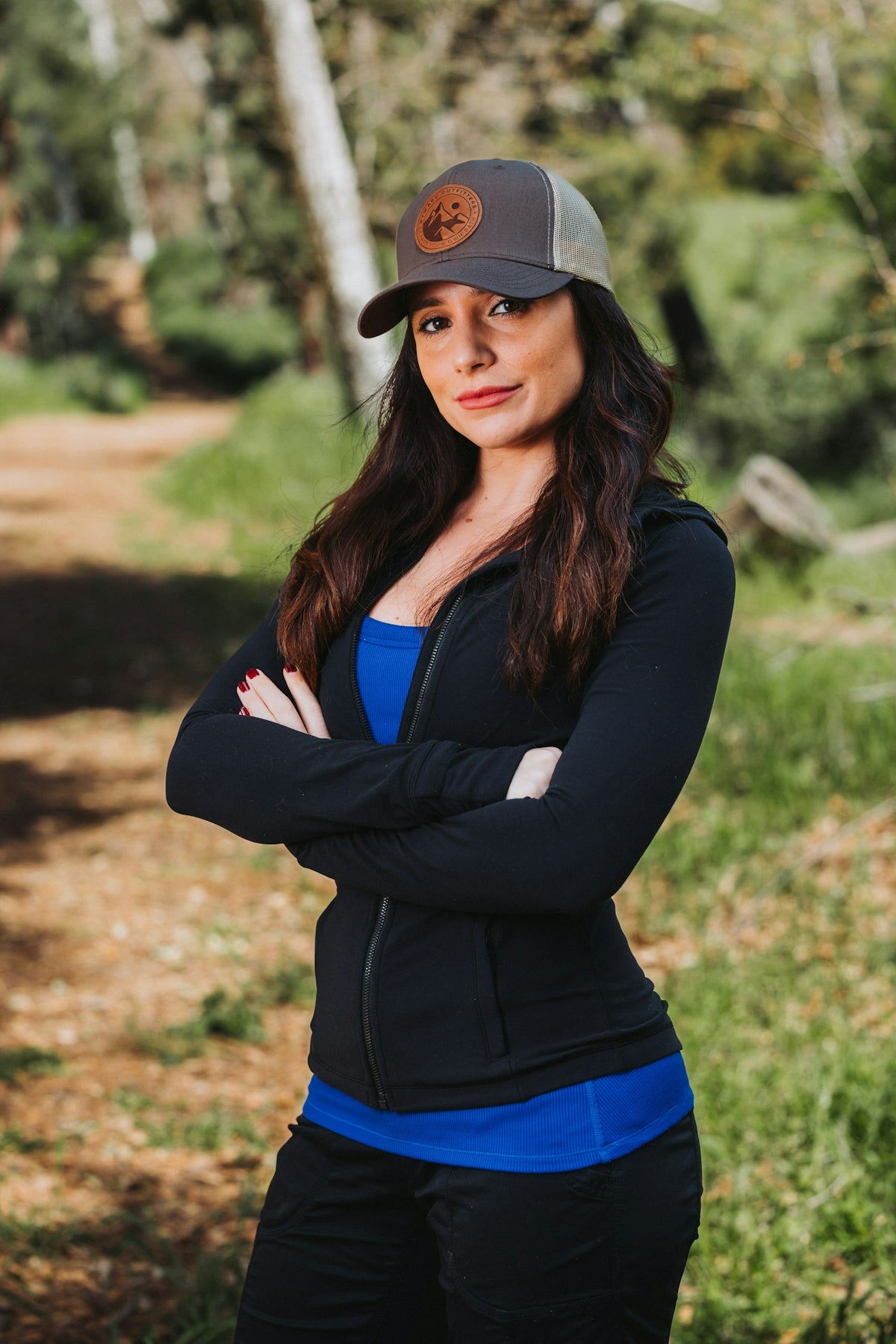 A woman wearing a hat standing in the woods