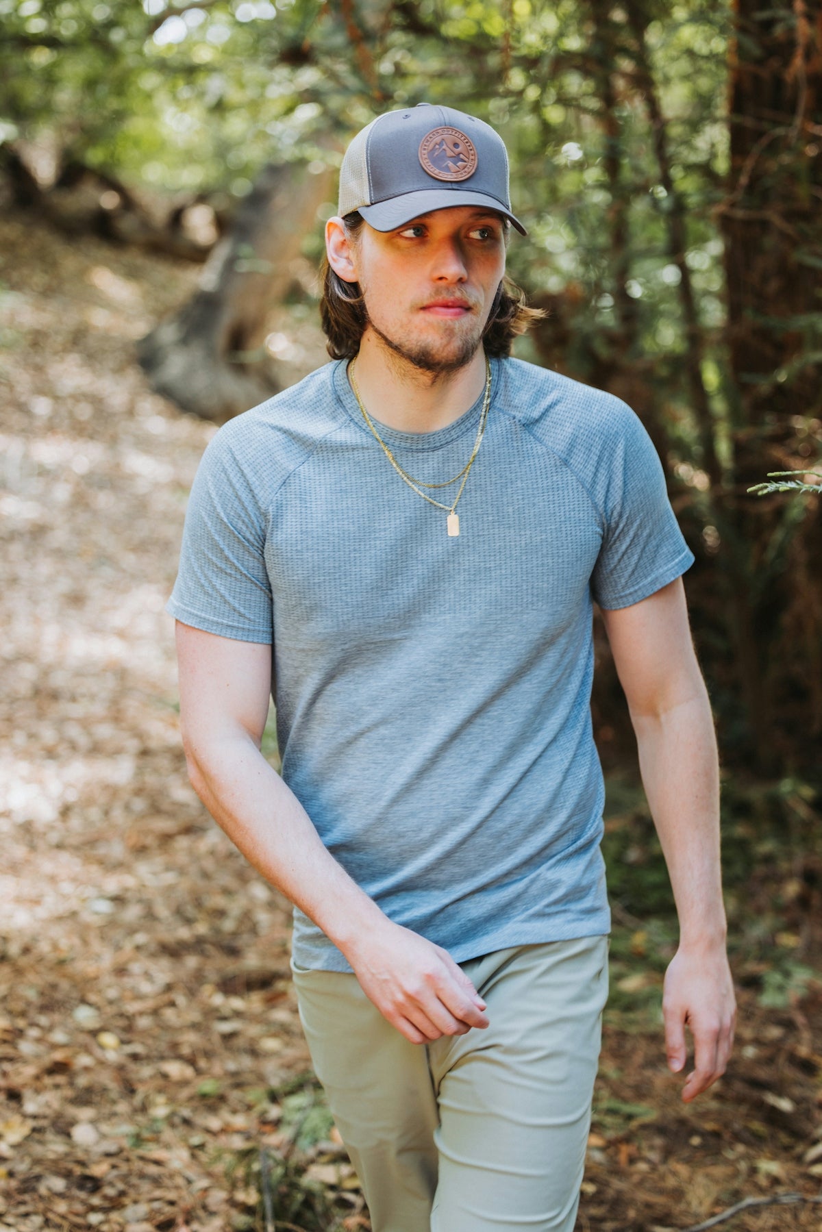A man in a hat is walking through the woods