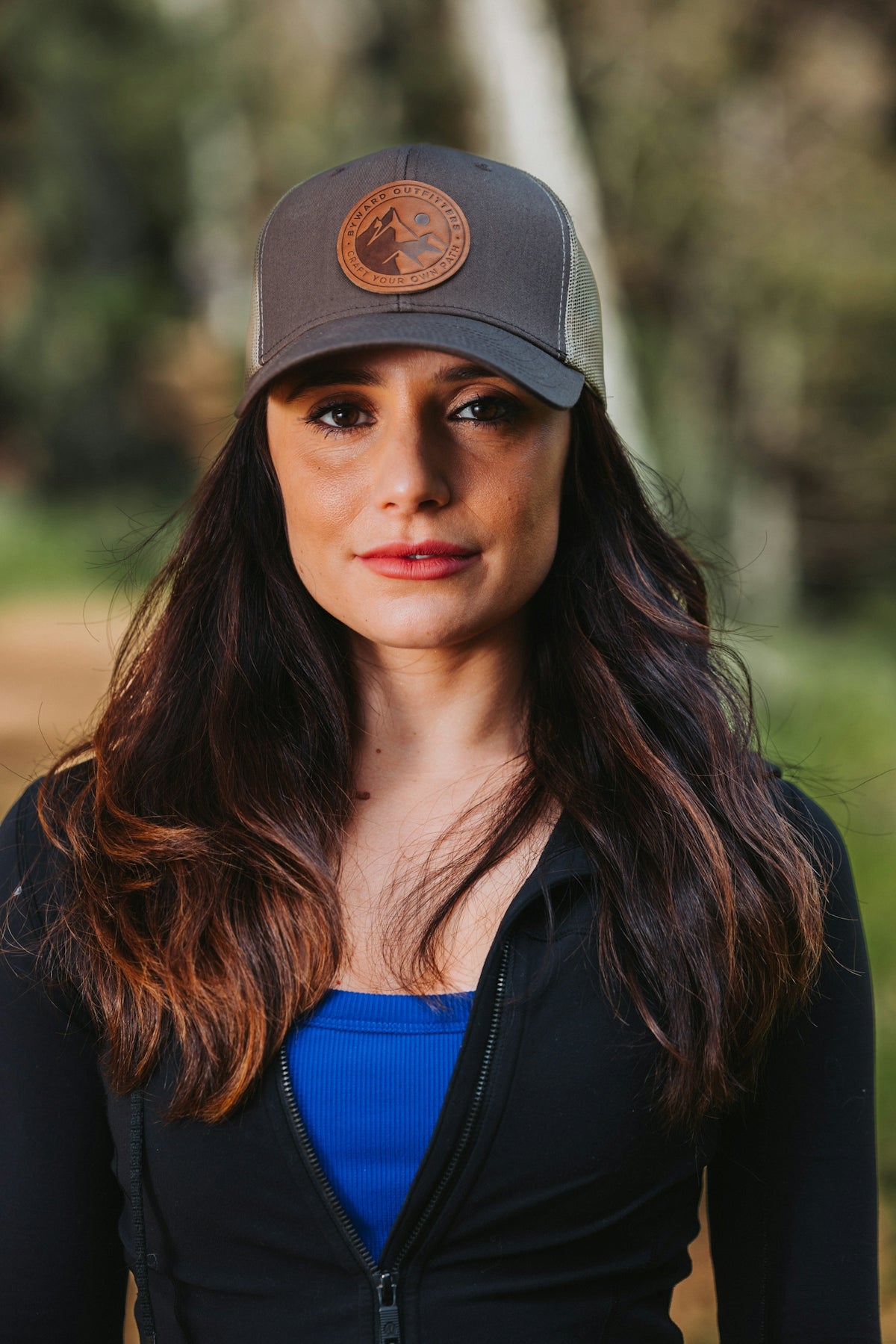 A woman wearing a hat standing in the woods