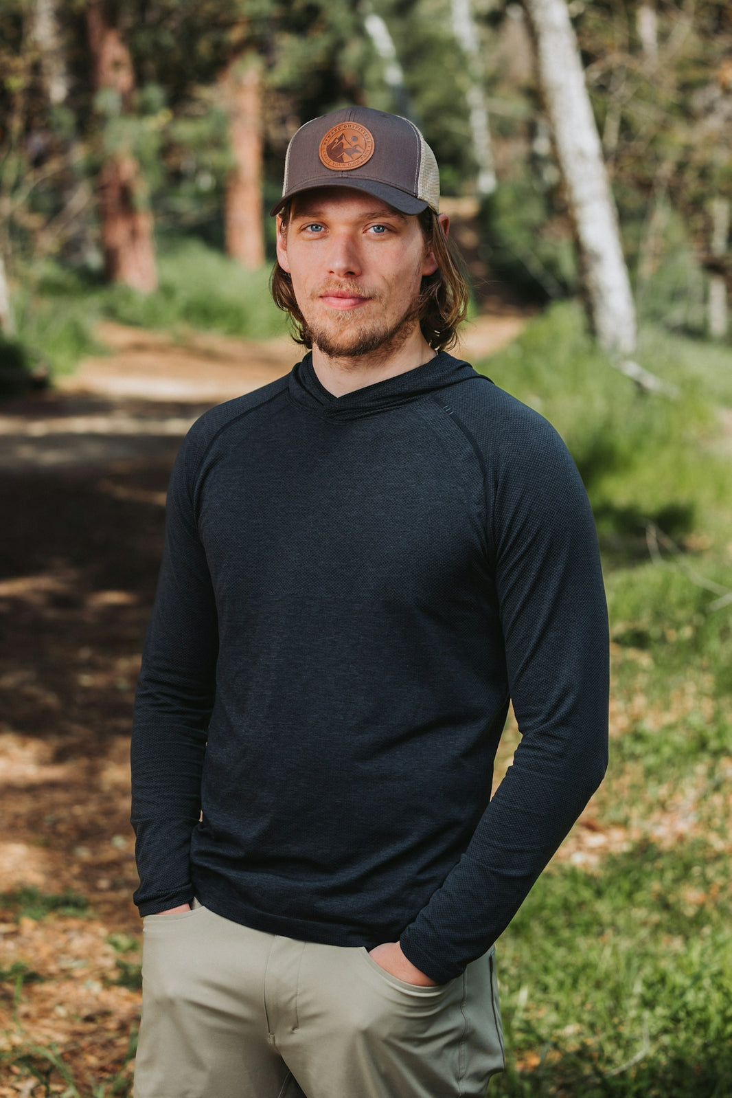 A man standing in the woods wearing a hat