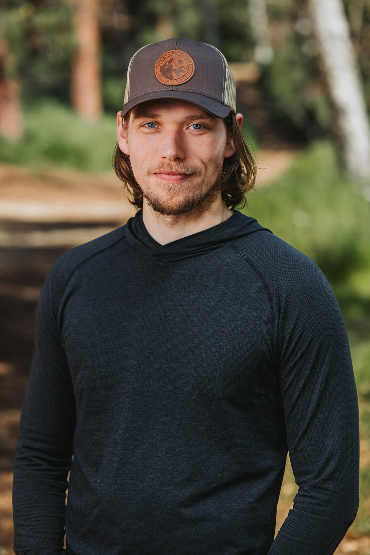 A man wearing a hat standing in the woods