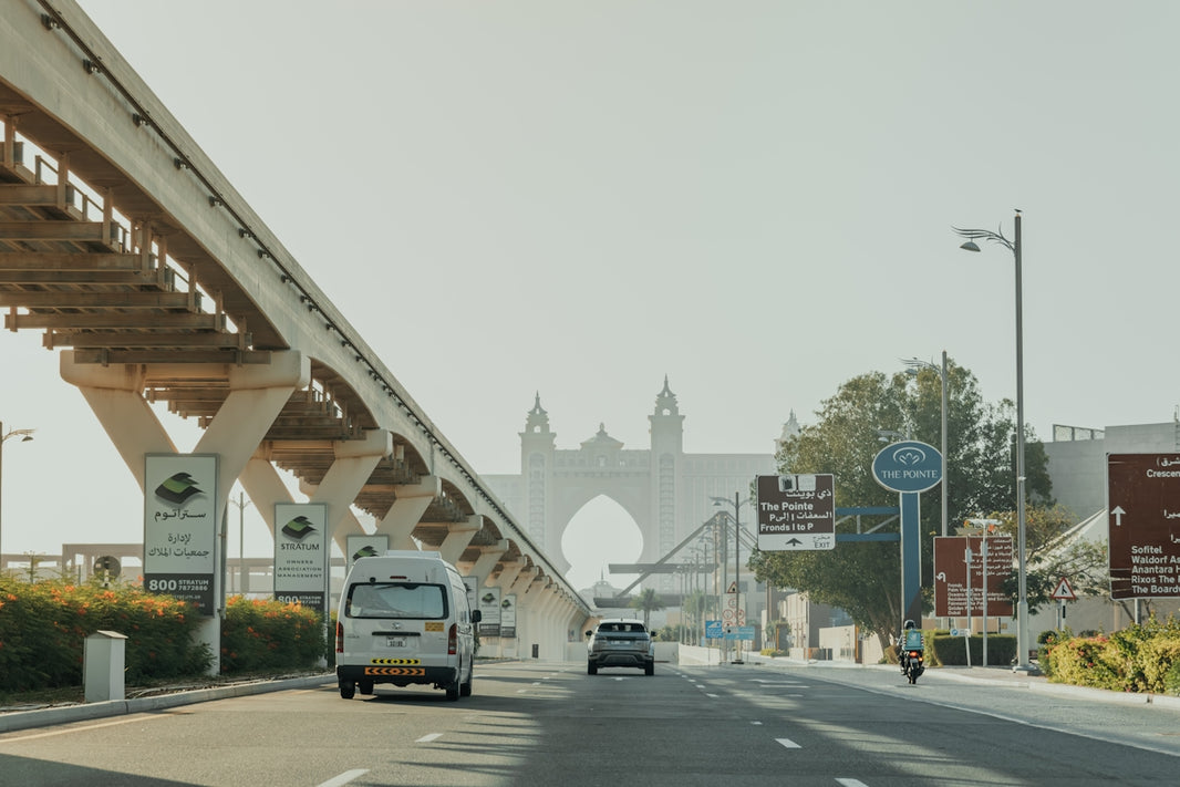 A white van driving down a street next to a bridge