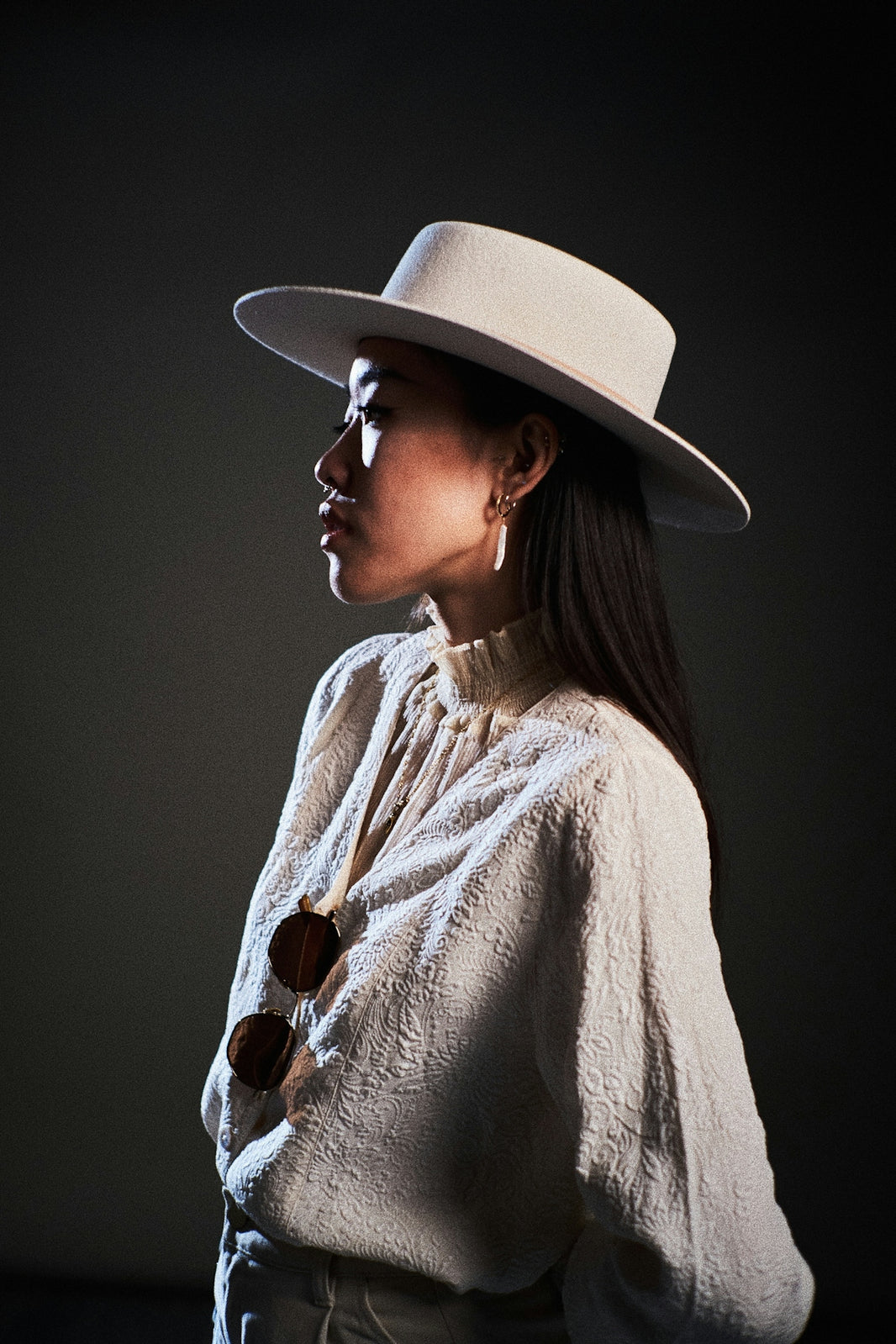 A woman in a hat poses sideways.