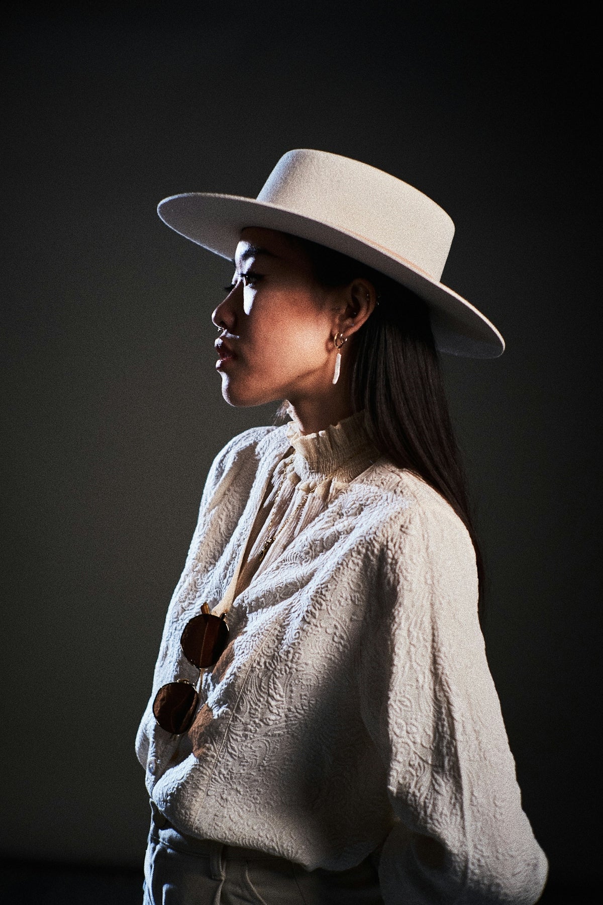 A woman in a hat poses sideways.