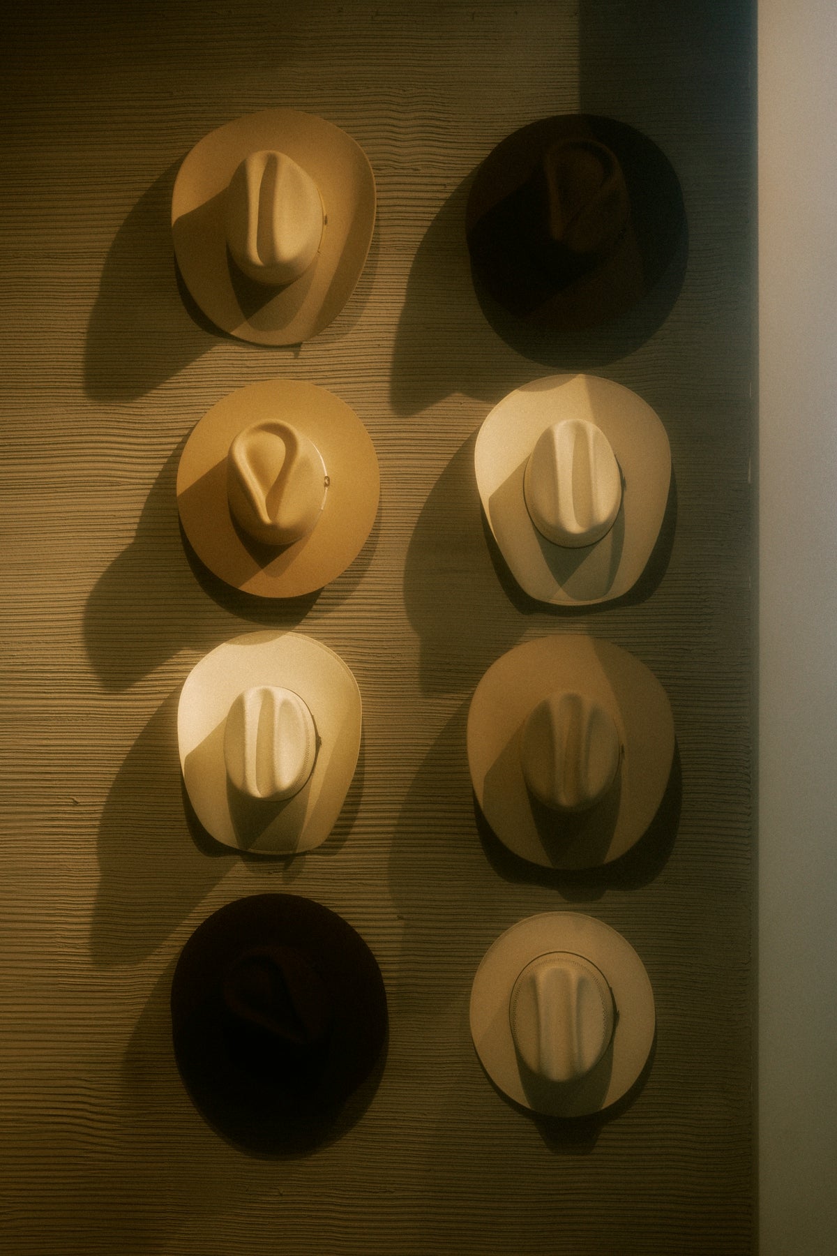 Cowboy hats are hanging in a neat vertical row.