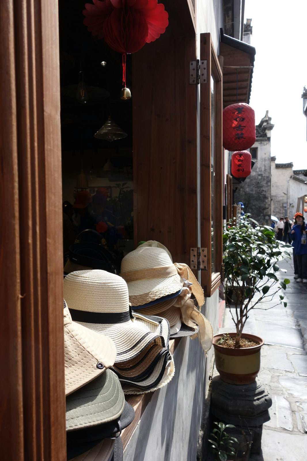 Hats displayed in a shop window along a street.