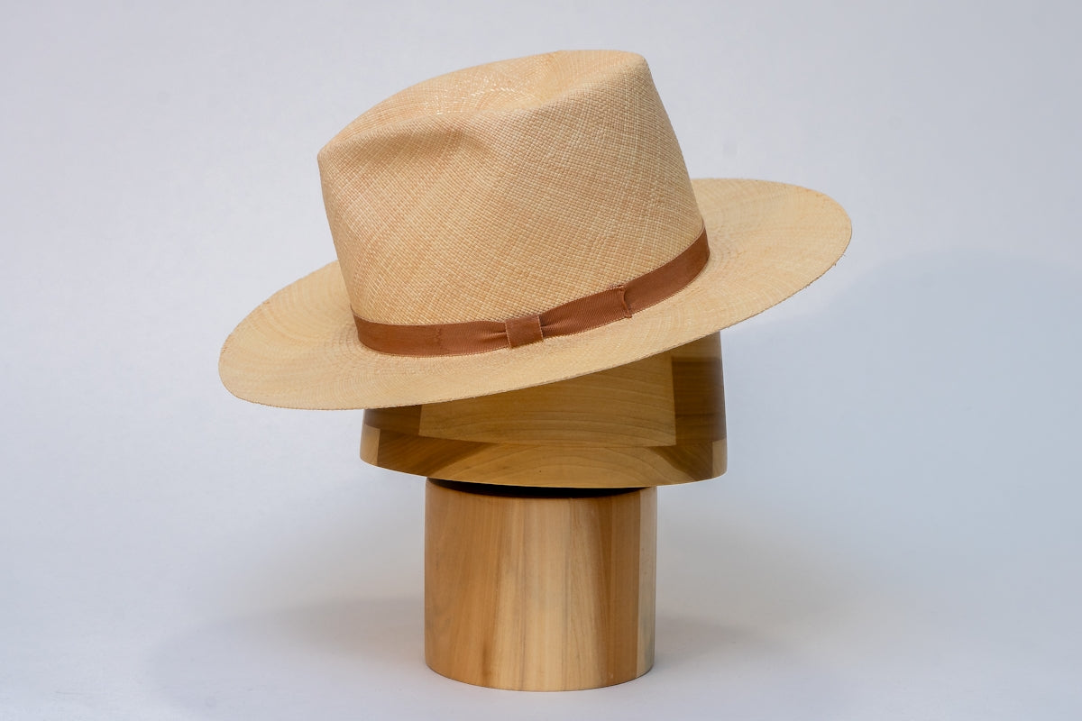 A stylish hat rests atop a wooden form.