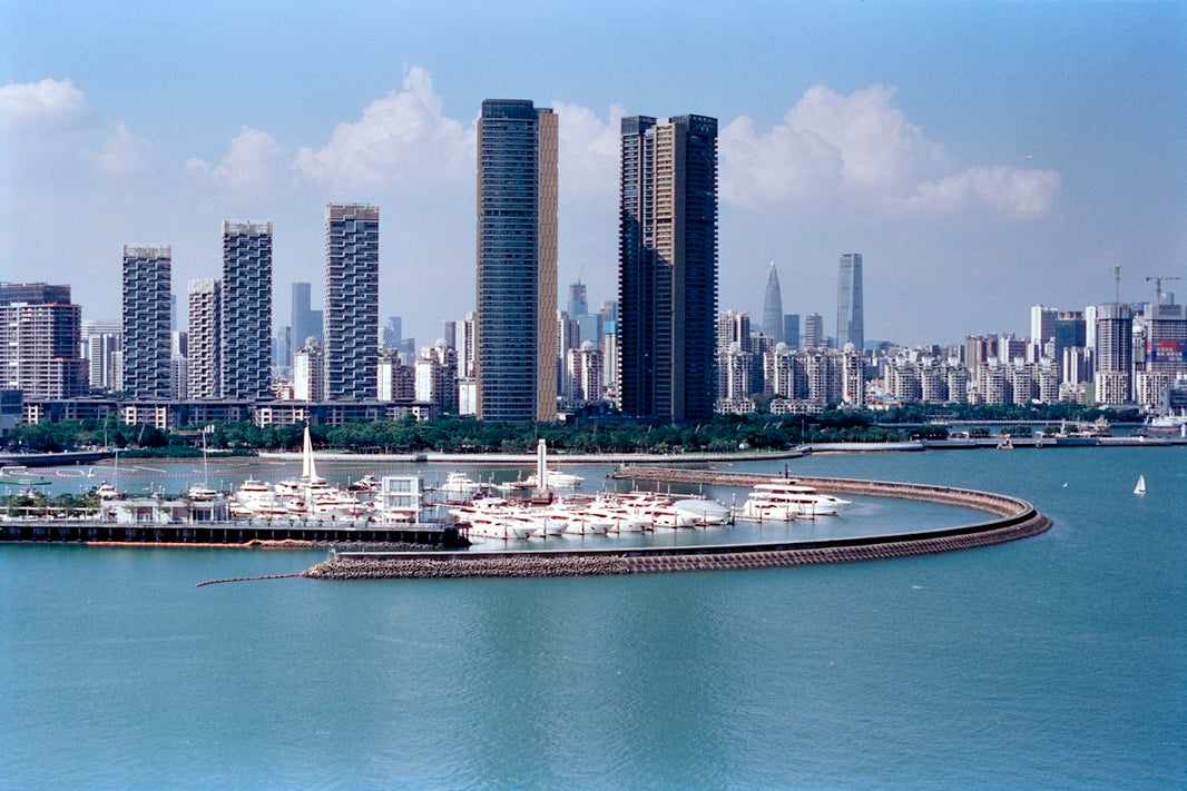 Modern cityscape with yachts docked in a harbor.