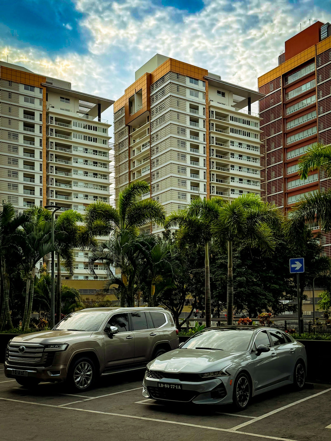 Two cars parked in front of modern buildings