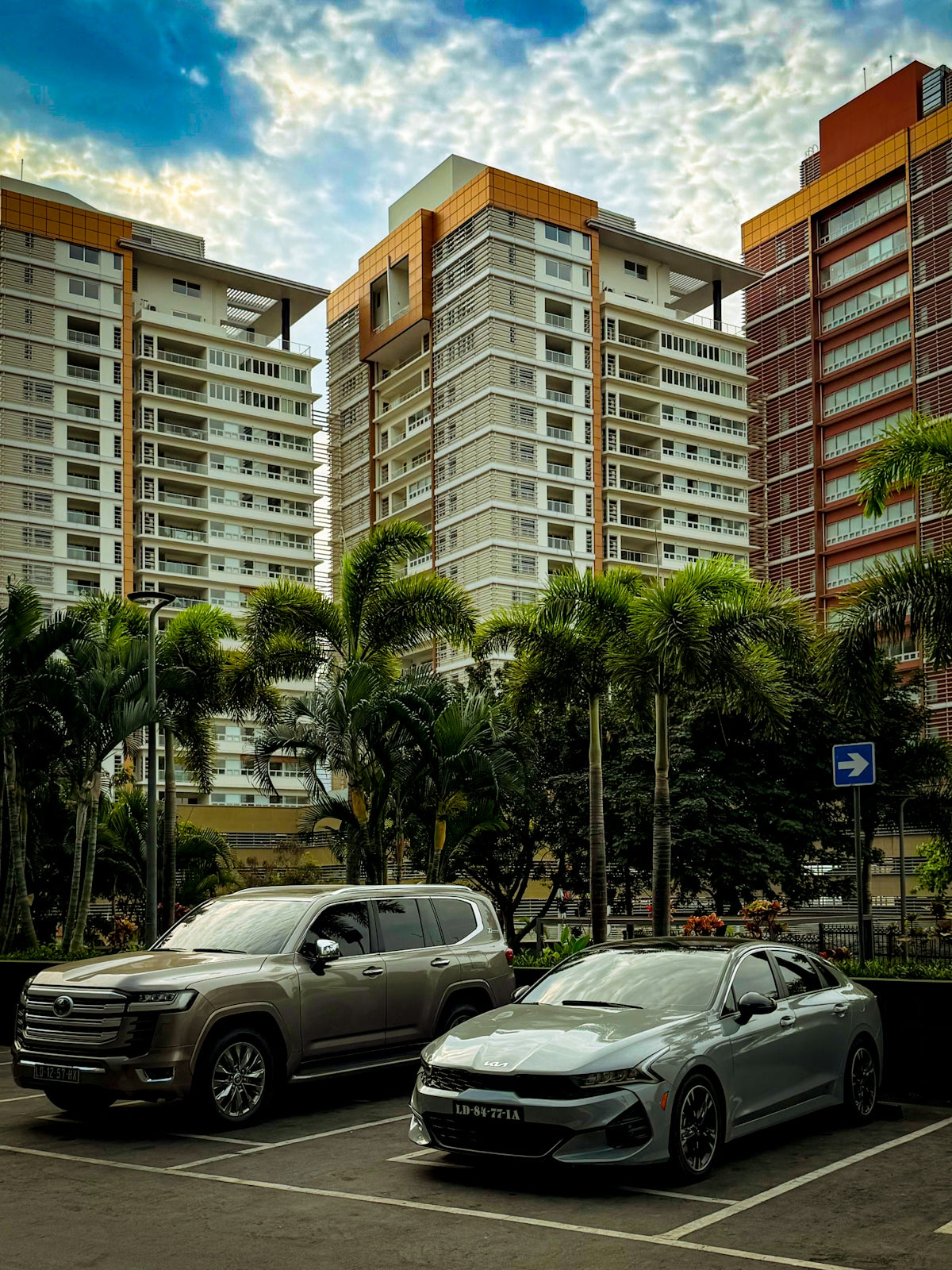 Two cars parked in front of modern buildings