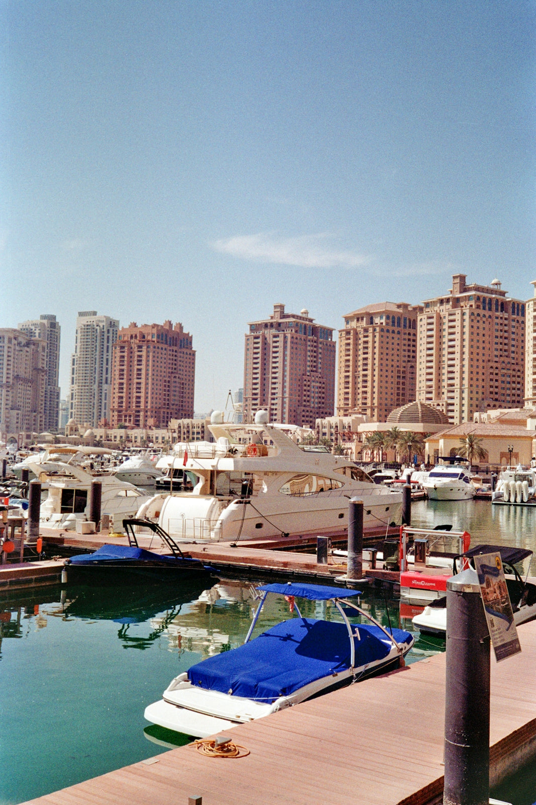 Luxury yachts docked in a modern marina with buildings.
