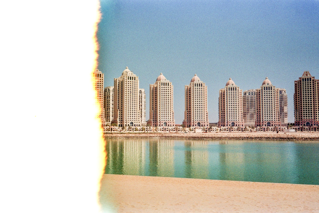Modern buildings line a waterfront with reflections.