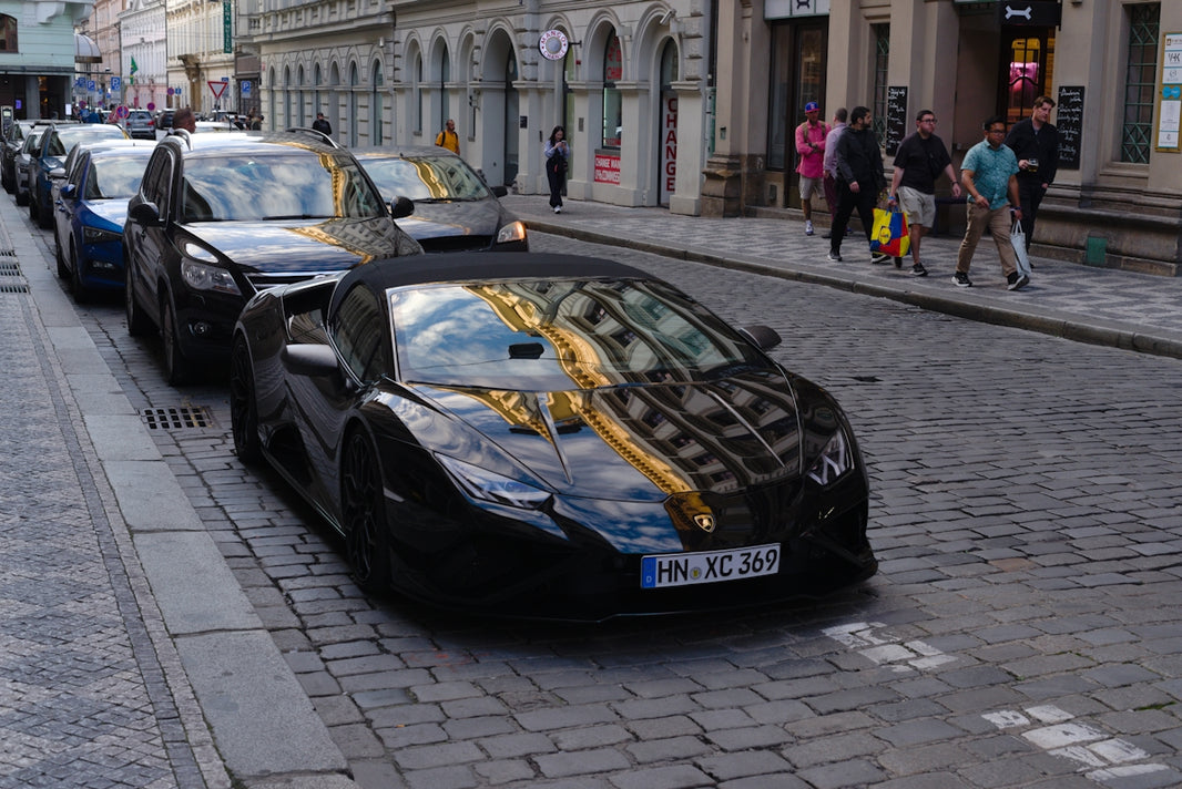 Black convertible car parked on cobblestone street.