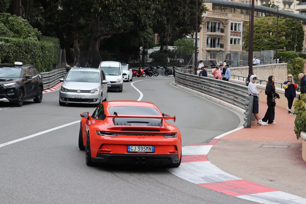 Orange sports car driving on a winding road.