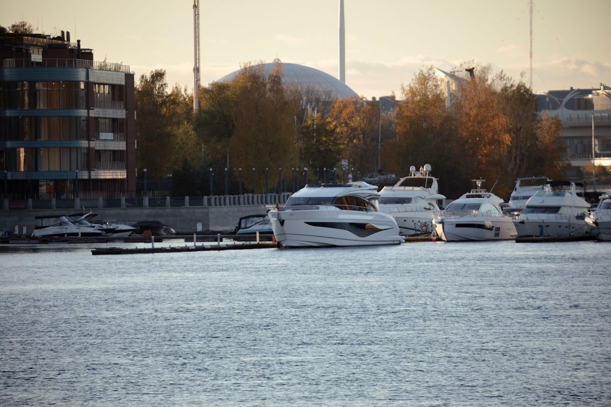 Modern yachts docked in a calm harbor at sunset.