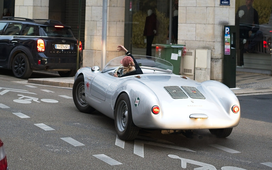 Silver vintage convertible driving on a city street.